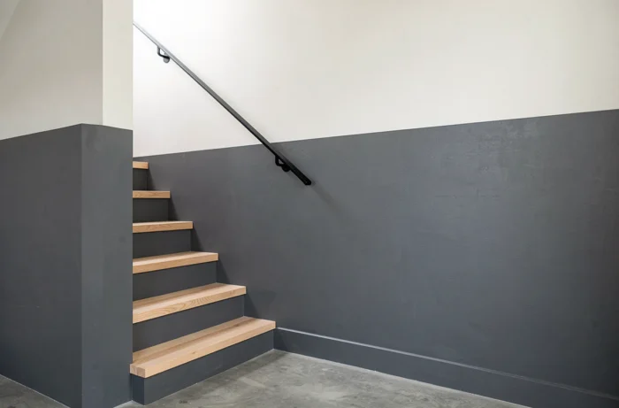 Mur de cage d'escalier peint en deux couleurs contrastées, gris ardoise en bas et blanc cassé en haut, avec une ligne de séparation nette pour casser la hauteur.