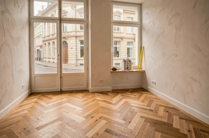 Intérieur rénové d'un appartement belge avec parquet en chêne et vue sur une rue bruxelloise Art Nouveau